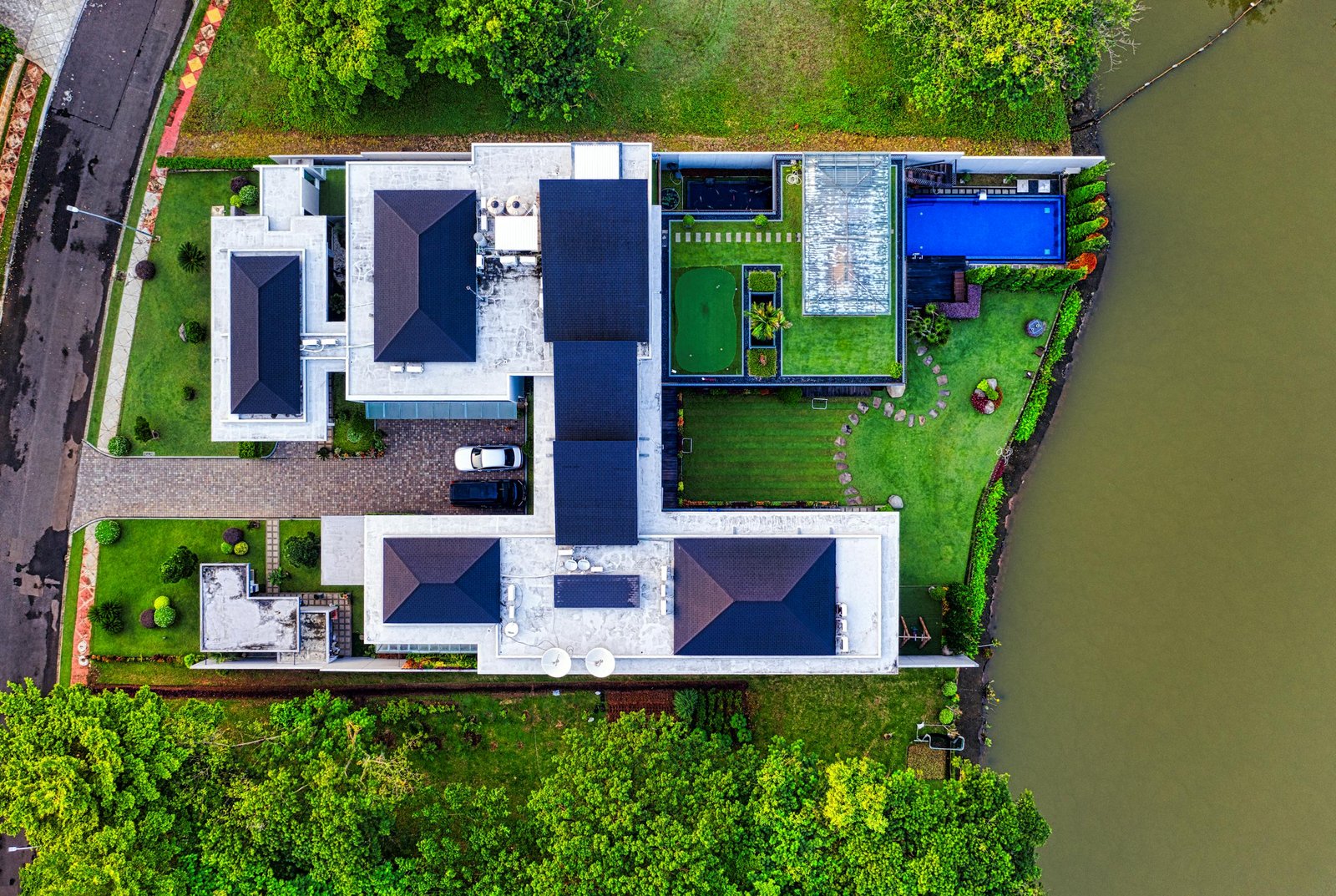 A stunning aerial view of a modern mansion in Banten, Indonesia, showcasing its architectural design and scenic surroundings.