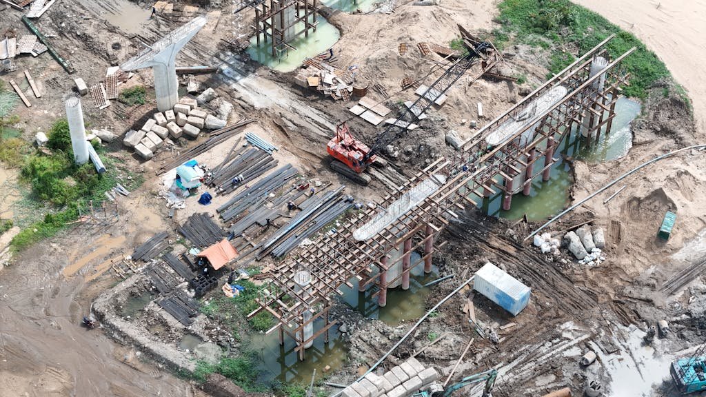 Aerial shot showcasing bridge construction with cranes and materials on site.
